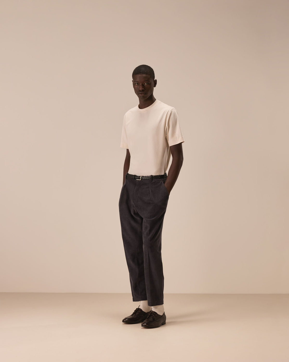 Model wearing a off white coloured tshirt tucked in to a pair of dark brown trousers and black shoes. Model is stood with his hands in his pockets in front of a off white coloured studio backdrop.  Circolo 1901 T-Shirt available at Sakks Menswear in Southampton.