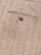 Close-up of a beige and brown herringbone tweed fabric with a single dark button and a stitched seam detail. Circolo 1901 Trousers available at Sakks Menswear in Southampton.