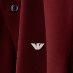 Close-up of a dark red textured knit garment with a small white embroidered logo and a dark button, showing fabric texture and branding. Emporio Armani Polo available at Sakks Menswear in Southampton