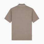 A short-sleeve polo shirt shown from the back, in a muted taupe-brown color with a thin white piping detail around the collar, displayed on a clean white background. Emporio Armani olo available at Sakks Menswear in Southampton.