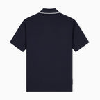 A dark navy blue short-sleeve polo shirt shown from the back, featuring a white contrast trim along the collar, set against a plain white background. Emporio Armani Polo available at Sakks Menswear in Southampton.