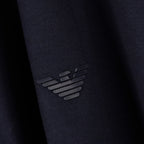 Close-up of a dark navy knit fabric with a tonal black embroidered Emporio Armani eagle logo. Emporio Armani Polo available at Sakks Menswear in Southampton.