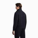 A man shown from the back wearing a dark navy or black mock-neck long-sleeve top and matching pants against a plain white studio background. Emporio Armani Sweatshirt available at Sakks Menswear in Southampton.