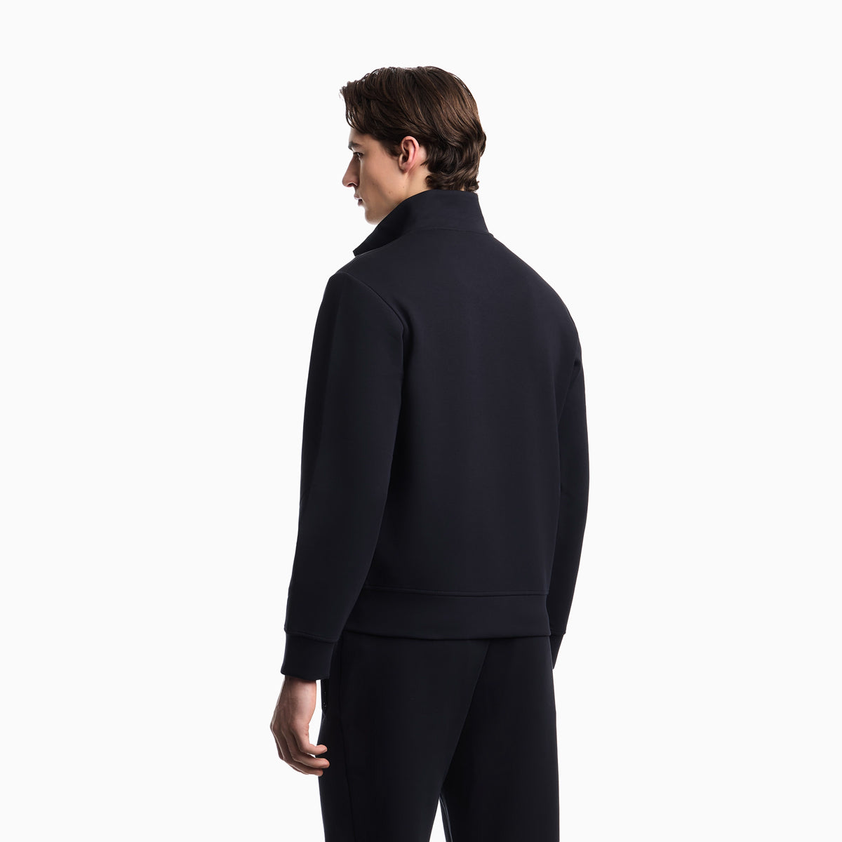 A man shown from the back wearing a dark navy or black mock-neck long-sleeve top and matching pants against a plain white studio background. Emporio Armani Sweatshirt available at Sakks Menswear in Southampton.
