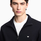 Man wearing a black jacket with a logo on a white background. Emporio Armani Sweatshirt available at Sakks Menswear in Southampton.
