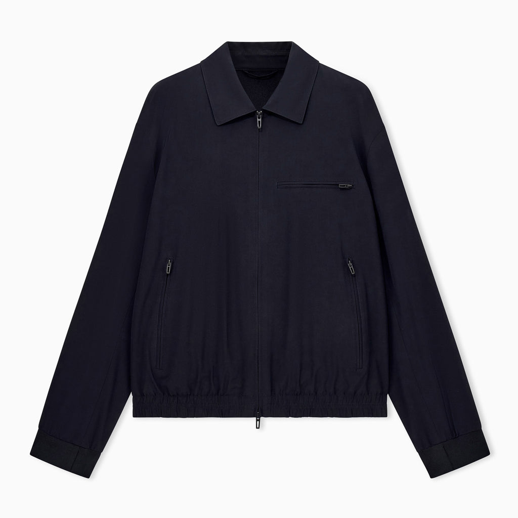 A dark navy blue lightweight jacket with a collar, front zipper, and zippered chest pocket, displayed flat against a light gray background. Emporio Armani Jacket available at Sakks Menswear in Southampton.
