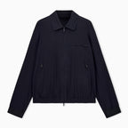 A dark navy blue lightweight jacket with a collar, front zipper, and zippered chest pocket, displayed flat against a light gray background. Emporio Armani Jacket available at Sakks Menswear in Southampton.