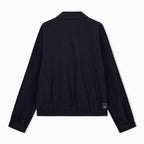 A dark navy blue jacket shown from the back, featuring a short stand collar, long sleeves with ribbed cuffs, and a small rectangular brand patch near the lower right hem, set against a plain white background. Emporio Armani Jacket available at Sakks Menswear in Southampton.