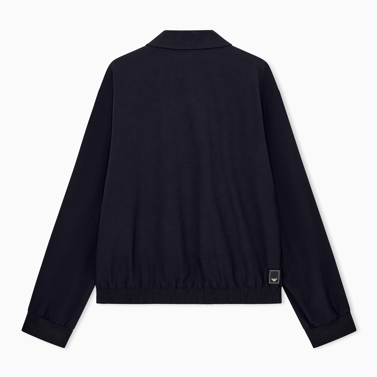 A dark navy blue jacket shown from the back, featuring a short stand collar, long sleeves with ribbed cuffs, and a small rectangular brand patch near the lower right hem, set against a plain white background. Emporio Armani Jacket available at Sakks Menswear in Southampton.