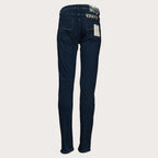 Back view of dark blue slim-fit jeans with a white paper tag attached to the back pocket, displayed on a light beige background. Jacob Cohen Jeans available at Sakks Menswear in Southampton.