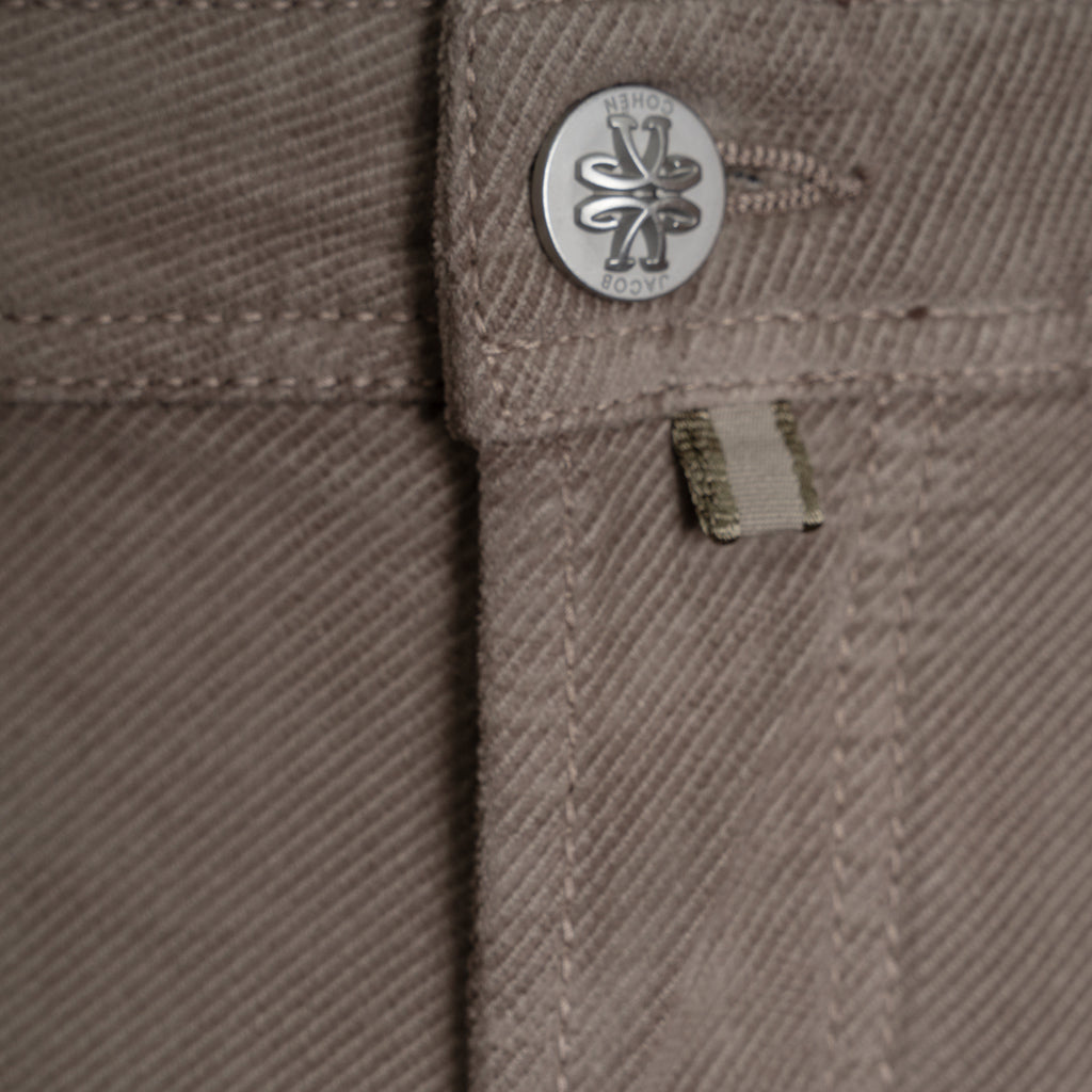 Close-up of a pair of brown twill pants showing the waistband details, including a silver metal button with a logo and a small fabric tab. Jacob Cohen Trousers available at Sakks Menswear in Southampton.