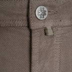 Close-up of a pair of brown twill pants showing the waistband details, including a silver metal button with a logo and a small fabric tab. Jacob Cohen Trousers available at Sakks Menswear in Southampton.