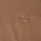 Close-up of a brown ribbed knit fabric with a tonal embroidered logo in the center. Jacob Cohen T-Shirt available at Sakks Menswear in Southampton.