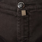 Close-up of dark charcoal gray denim fabric showing a silver metal button with a stylized logo and a small beige fabric brand tab. Jacob Cohen Trousers available at Sakks Menswear in Southampton.