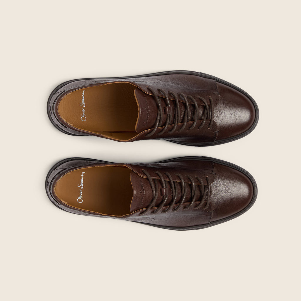 A pair of dark brown leather lace-up shoes shown from a top-down view on a light beige background. The brand name 'Oliver Sweeney' is visible on the insoles. Oliver Sweeney Shoes are available at Sakks Menswear in Southampton.