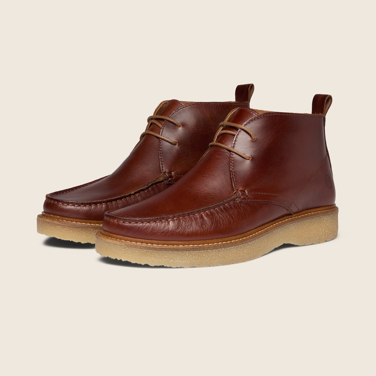 A pair of classic brown leather ankle boots with tan soles, displayed on a clean, light beige background. Oliver Sweeney Moccasin Boots Available at Sakks Menswear in Southampton.