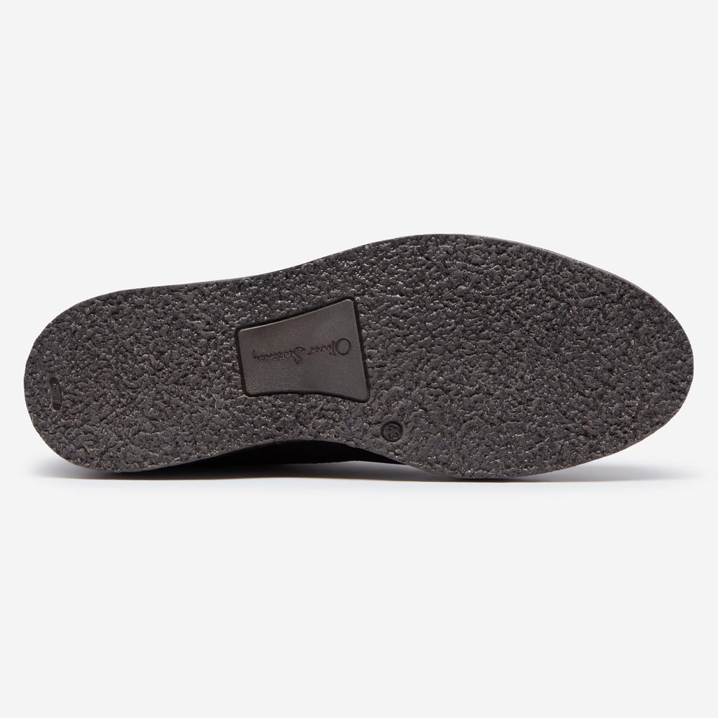 The textured black rubber outsole of a shoe, showing a central brand patch that reads 'Oliver Sweeney' on a clean white background. Oliver Sweeney Moccasin's available at Sakks Menswear in Southampton.