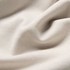 A close-up of draped cream-colored fabric with soft folds and a fine woven texture. Oliver Sweeney T-Shirt available at Sakks Menswear in Southampton.