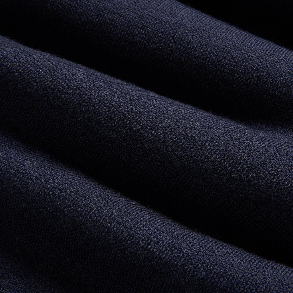A close-up of dark navy blue knit fabric with soft diagonal folds and a visible woven texture. Oliver Sweeney Sweater available at Sakks Menswear in Southampton.