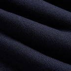 A close-up of dark navy blue knit fabric with soft diagonal folds and a visible woven texture. Oliver Sweeney Sweater available at Sakks Menswear in Southampton.