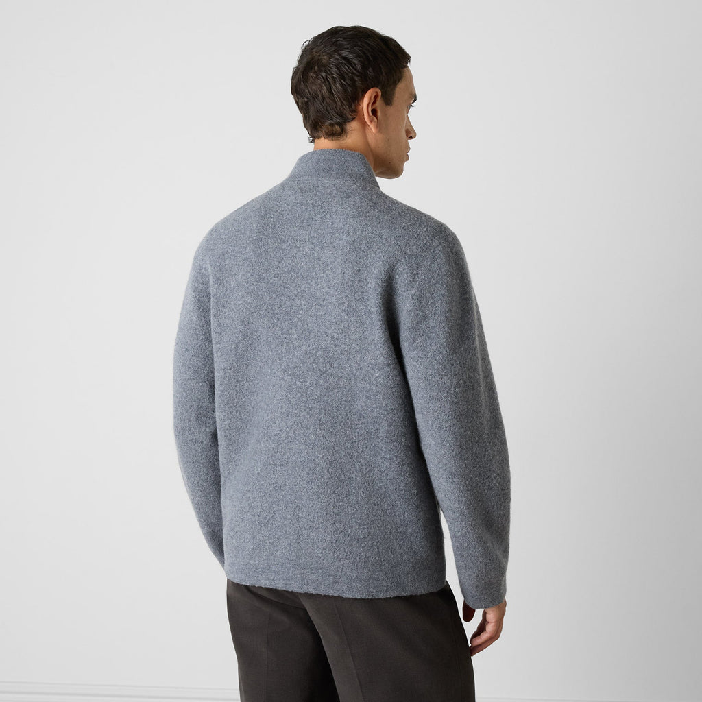A man wearing a gray knit mock-neck sweater, shown from the back against a plain light gray studio background. Oliver Sweeney Cardigan available at Sakks Menswear in Southampton.