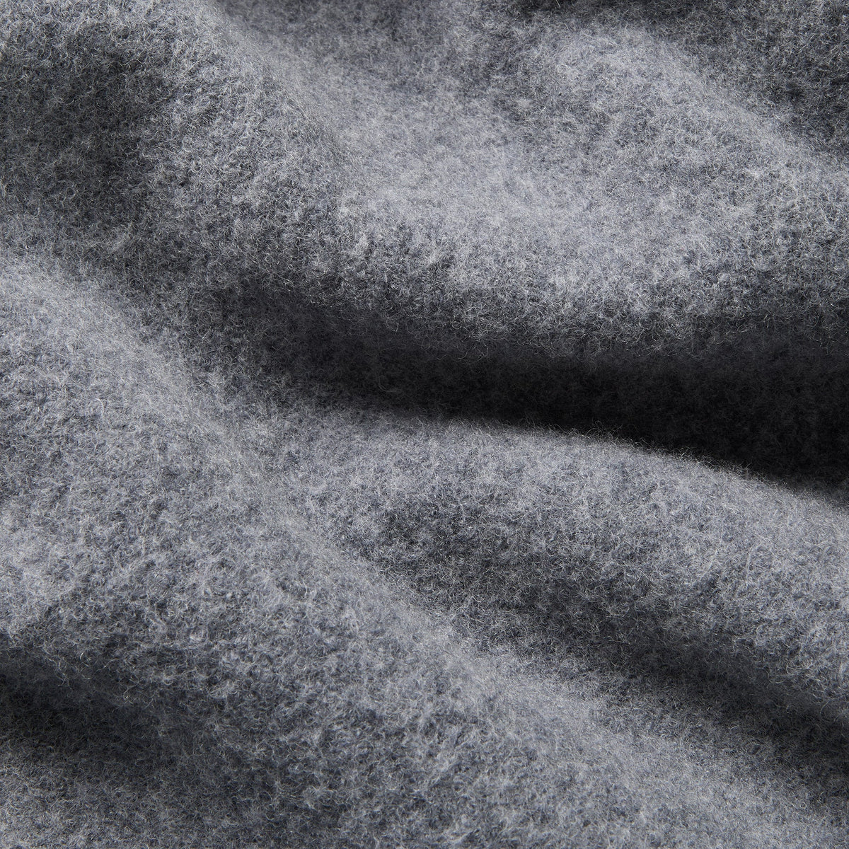 A close-up of textured gray fabric with soft folds and a heathered, slightly fuzzy surface. Oliver Sweeney Cardigan available at Sakks Menswear in Southampton.