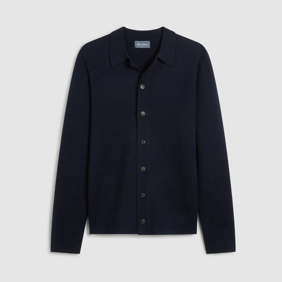Knitted navy merino wool blend overshirt lat laid on a light grey background. The overshirt is a button down closure. Oliver Sweeney cardigan available at Sakks Menswear in Southampton.