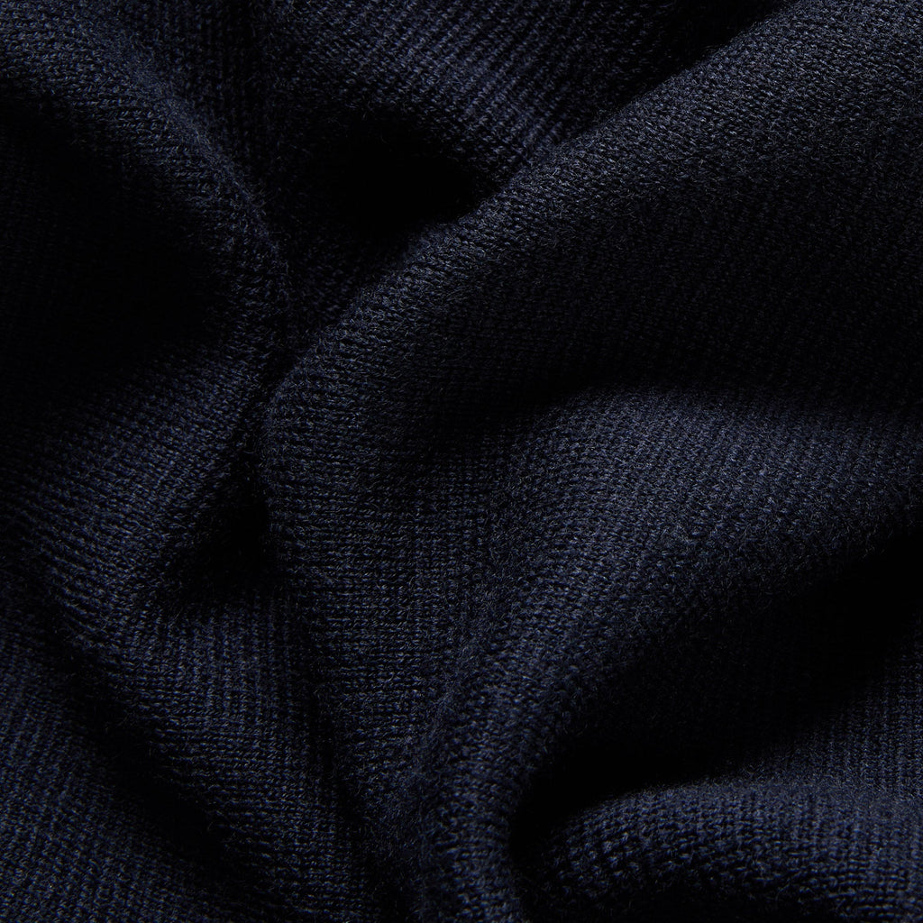 Close-up of dark navy ribbed knit fabric with soft folds and visible texture. Oliver Sweeney cardigan available at Sakks Menswear in Southampton.