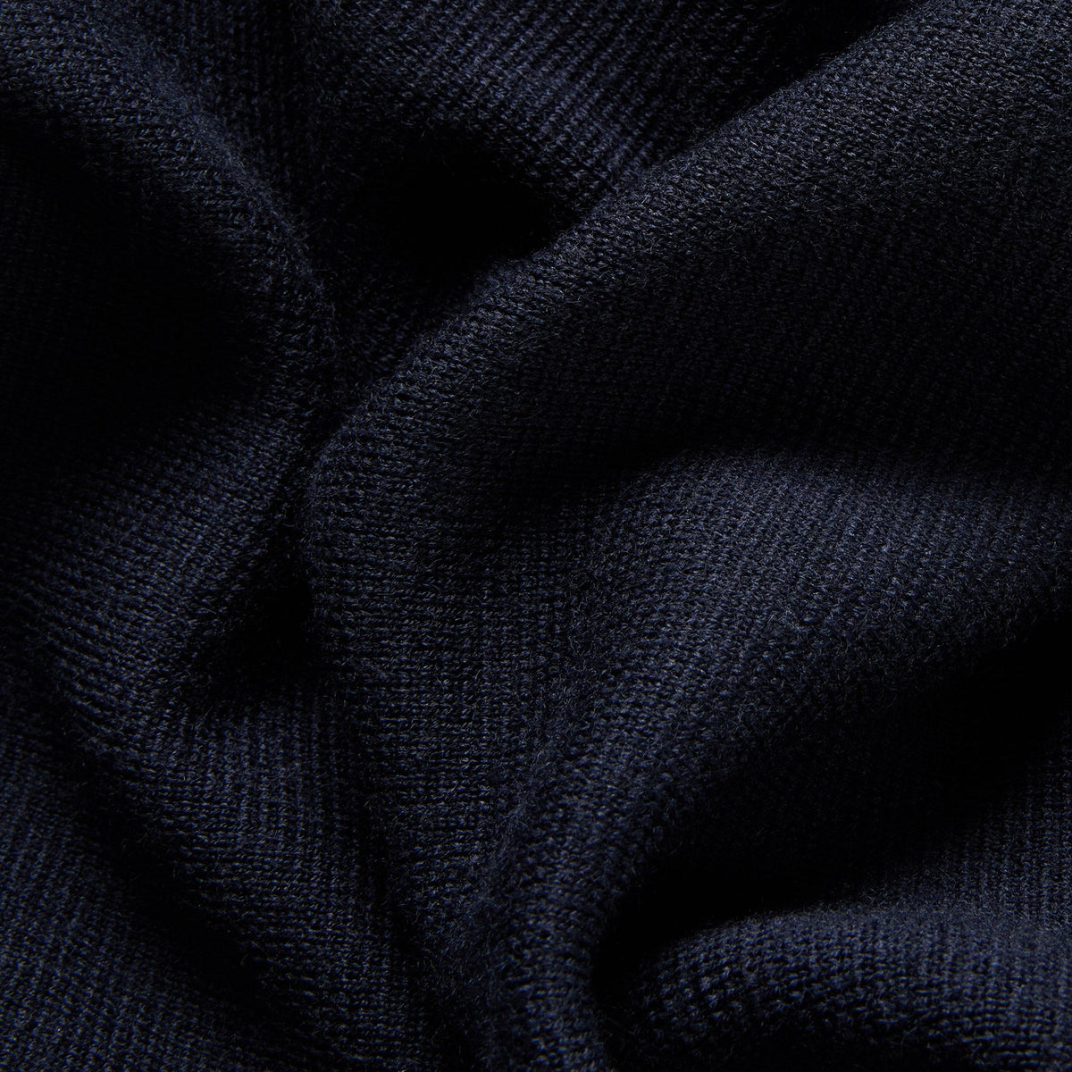 Close-up of dark navy ribbed knit fabric with soft folds and visible texture. Oliver Sweeney cardigan available at Sakks Menswear in Southampton.