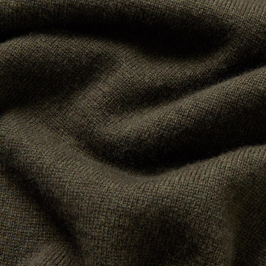 A close-up of dark olive green ribbed knit fabric with soft folds and shadows. Oliver Sweeney Knitwear available at Sakks Menswear in Southampton.