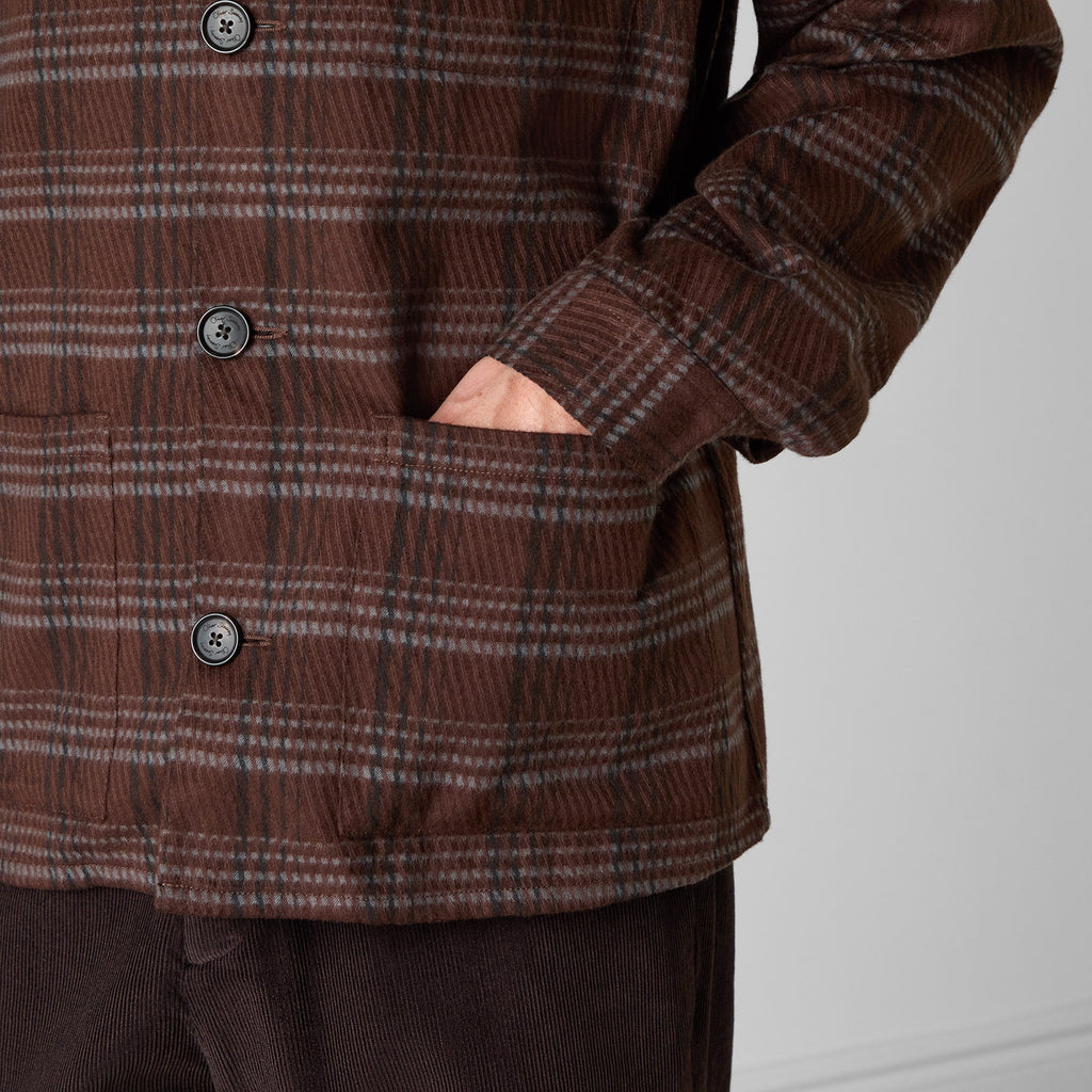 Close-up of a brown corduroy plaid jacket with a hand in the pocket, showing the button closure and fabric texture. Oliver Sweeney Shirt Jacket available at Sakks Menswear in Southampton.