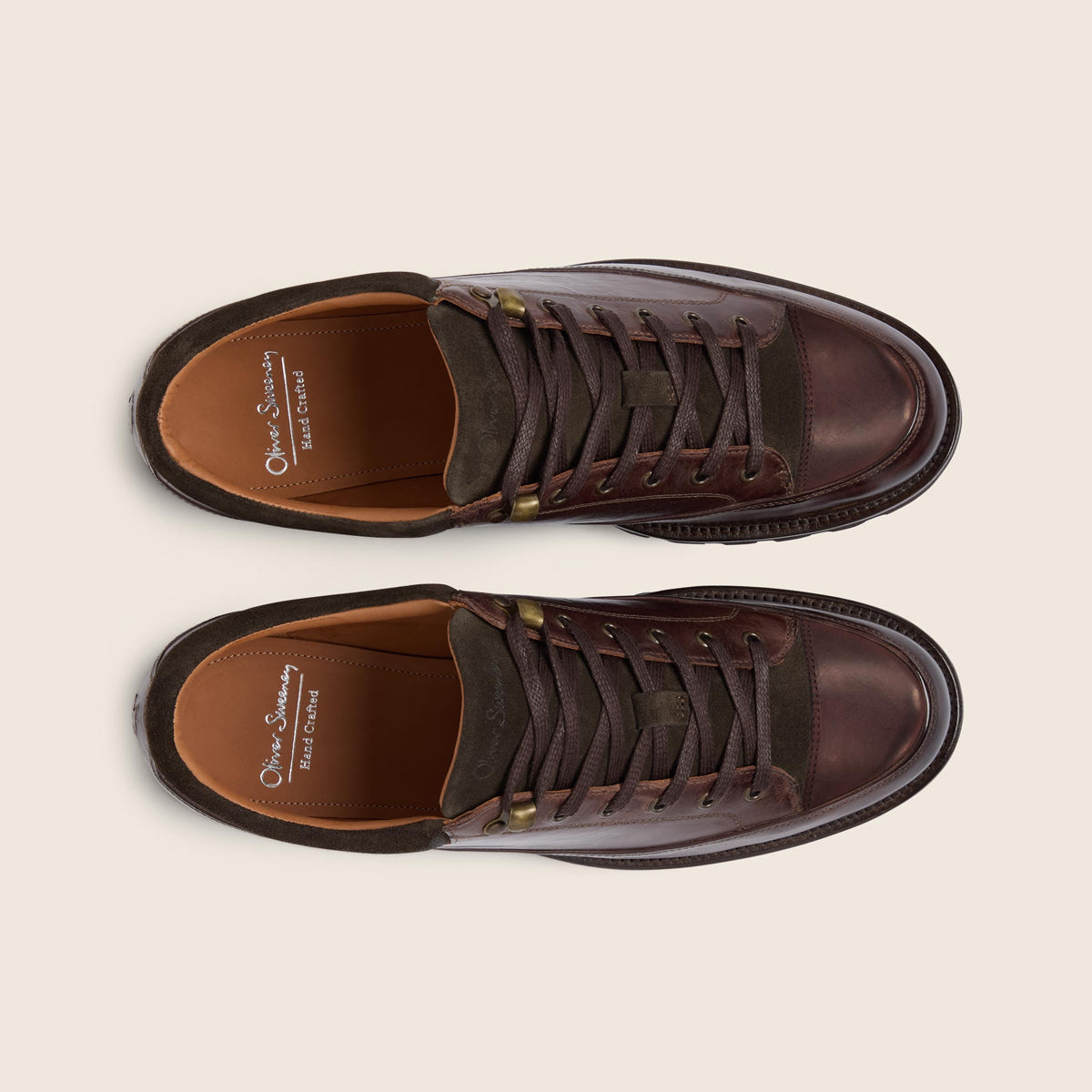A pair of dark brown leather low-top shoes with dark brown laces, shown from a top-down view on a light beige background. The brand 'Oliver Sweeney' is visible on the insoles. Oliver Sweeney Boots available at Sakks Menswear in Southampton.