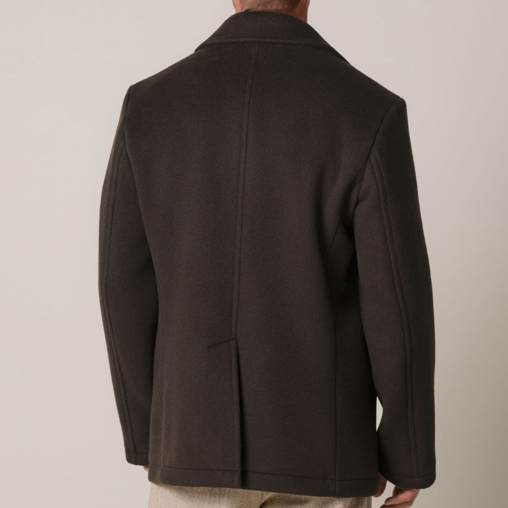 Rear view of a man wearing a dark brown wool blazer against a neutral beige background. Profuomo coat available at Sakks Menswear in Southampton.