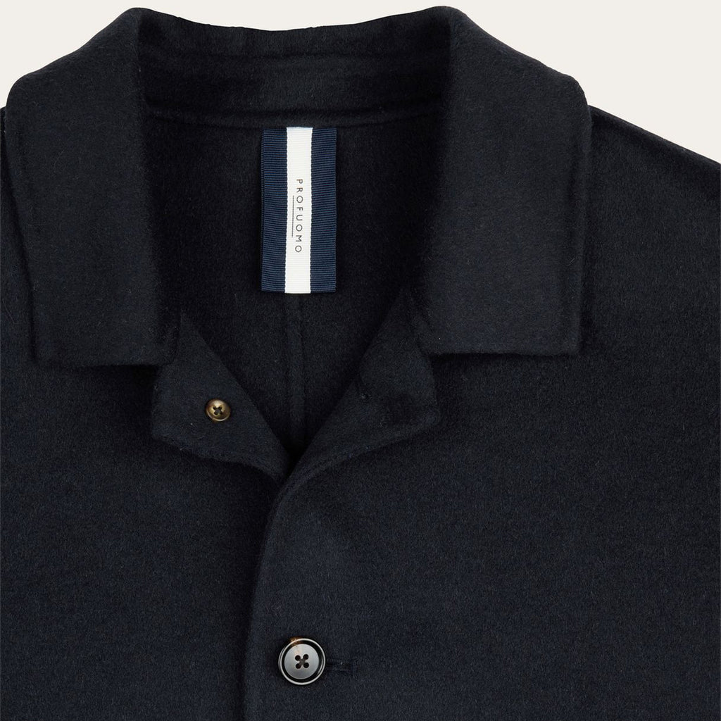 Close-up of a dark navy wool-blend polo shirt collar with a buttoned placket and a visible neck label reading PROFUOMO.  Profuomo Coat available at Sakks Menswear in Southampton.