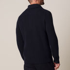 A man wearing a dark navy ribbed knit sweater, shown from a rear three-quarter view against a plain beige background. Profuomo Knitwear available at Sakks Menswear in Southampton.