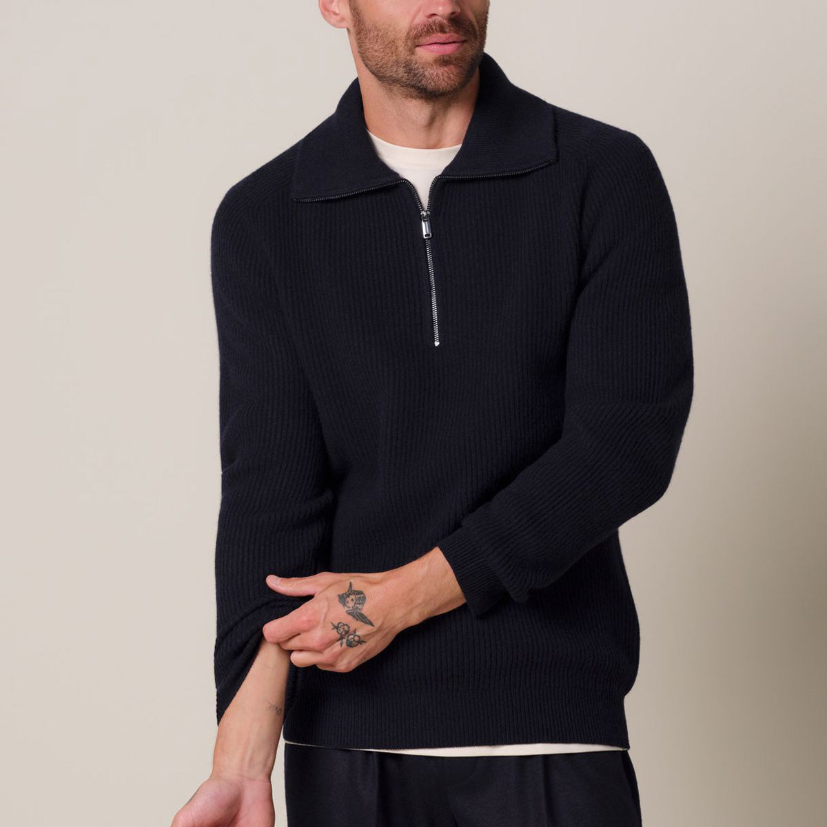 A man wearing a dark navy ribbed knit quarter-zip sweater over a white undershirt, shown from the chin down against a plain beige studio background. Profuomo Knitwear available at Sakks Menswear in Southampton.