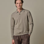 A man wearing a light taupe-gray long-sleeve quarter-zip polo sweater and brown trousers, standing against a solid neutral beige background. Profuomo Polo available at Sakks Menswear in Southampton.