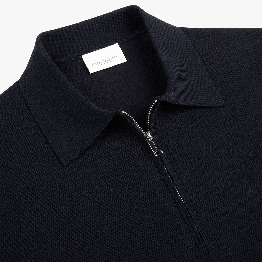 Close-up of a dark navy knit polo shirt with a collar, a silver zipper at the neck, and a white interior neck label reading PROFUOMO. Profuomo Polos available at Sakks Menswear in Southampton.
