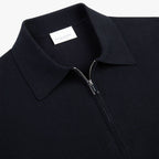 Close-up of a dark navy knit polo shirt with a collar, a silver zipper at the neck, and a white interior neck label reading PROFUOMO. Profuomo Polos available at Sakks Menswear in Southampton.