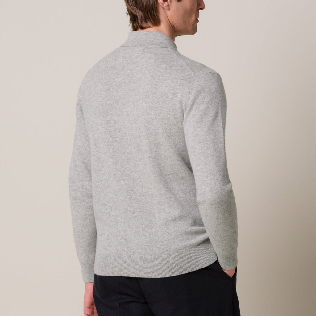 A man wearing a light gray heathered knit sweater, shown from a rear three-quarter angle against a plain beige studio background. Profuomo Knitwear available at Sakks Menswear in Southampton.
