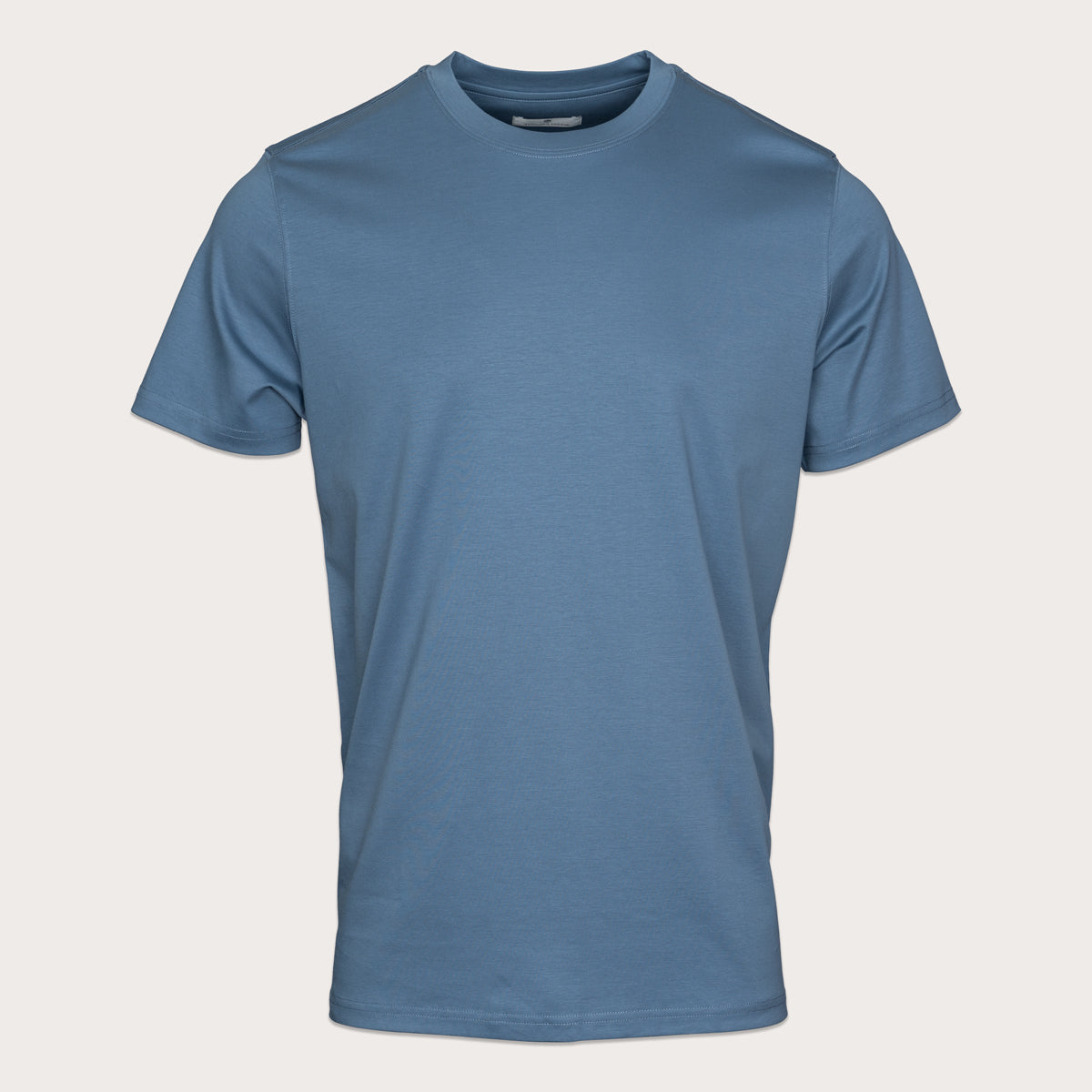 A short-sleeve crewneck t-shirt in a muted slate blue color, displayed on a clean, light beige background. Thomas Maine T-Shirts available at Sakks Menswear in Southampton.
