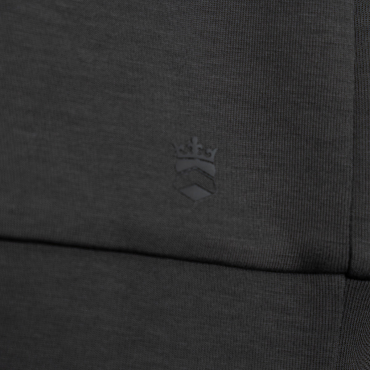 Close-up of dark heather gray ribbed fabric with a tonal embossed crown crest logo near the center. Thomas Maine Sweatshirt available at Sakks Menswear in Southampton.