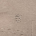 Close-up of a light beige knit fabric with a tonal embroidered crown logo centered on the chest. Thomas Maine Sweats available at Sakks Menswear in Southampton.