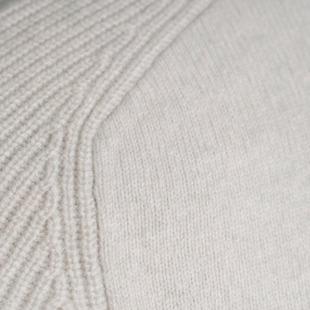 Close-up of a light cream knit fabric with a ribbed textured pattern on the left and a smoother knit section on the right. Thomas Maine Knitwear available at Sakks Menswear in Southampton.