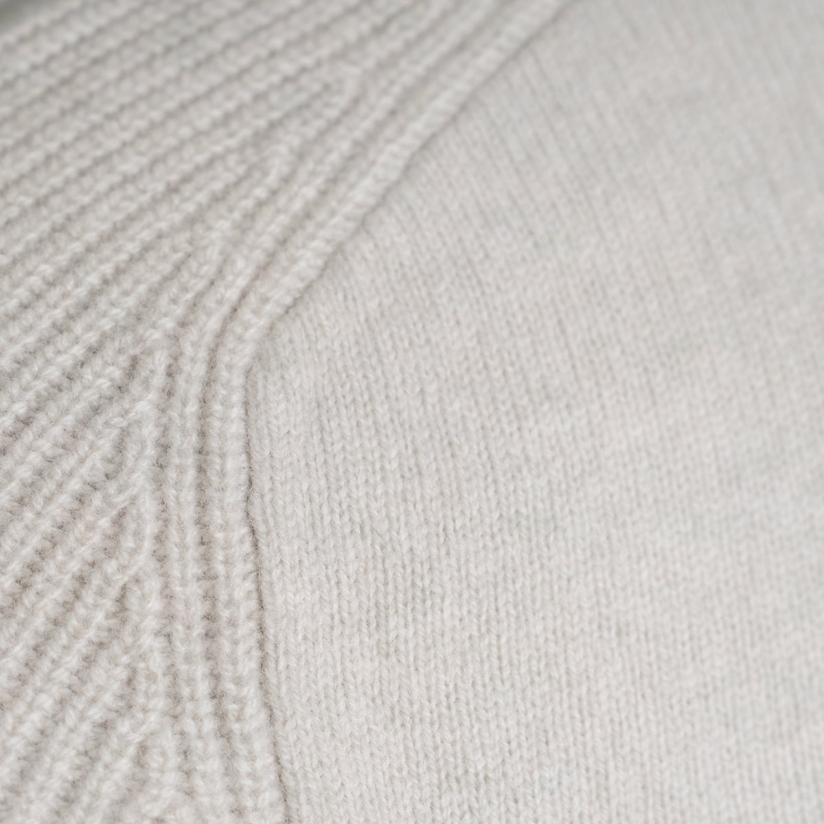 Close-up of a light cream knit fabric with a ribbed textured pattern on the left and a smoother knit section on the right. Thomas Maine Knitwear available at Sakks Menswear in Southampton.