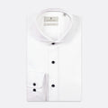 A white long-sleeve dress shirt by The Pillory, featuring a spread collar, button-down front, and a single-button cuff, shown on a light gray background. Thomas Maine shirts available at Sakks Menswear in Southampton.