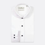 A white long-sleeve dress shirt by The Pillory, featuring a spread collar, button-down front, and a single-button cuff, shown on a light gray background. Thomas Maine shirts available at Sakks Menswear in Southampton.