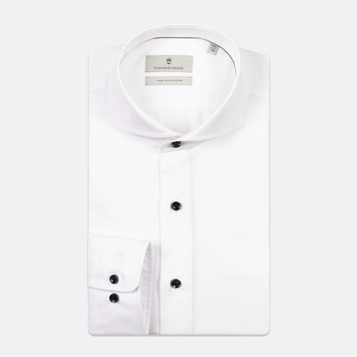 A white long-sleeve dress shirt by The Pillory, featuring a spread collar, button-down front, and a single-button cuff, shown on a light gray background. Thomas Maine shirts available at Sakks Menswear in Southampton.