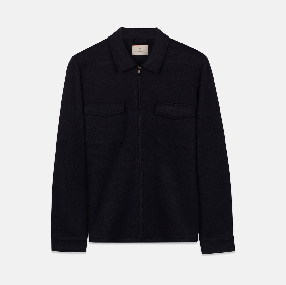 A dark navy blue zip-up jacket with a pointed collar, two chest flap pockets, and long sleeves, shown flat against a light gray background. Thomas Maine Overshirt available at Sakks Menswear in Southampton.