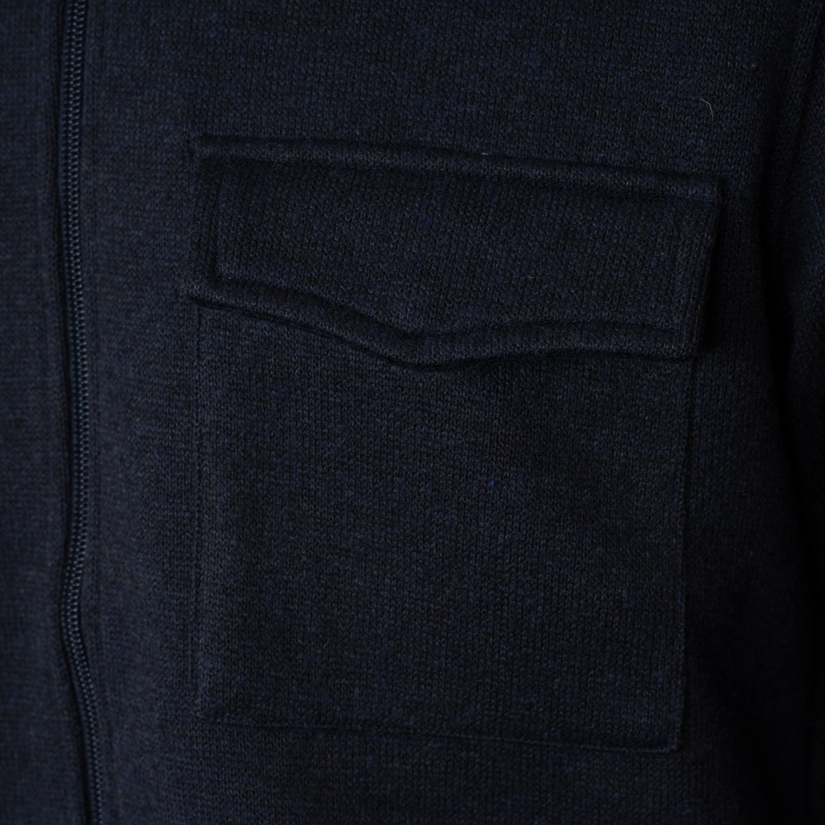 Close-up of a dark navy knit garment showing a front zipper and a large chest pocket. Thomas Maine Overshirt available at Sakks Menswear in Southampton.